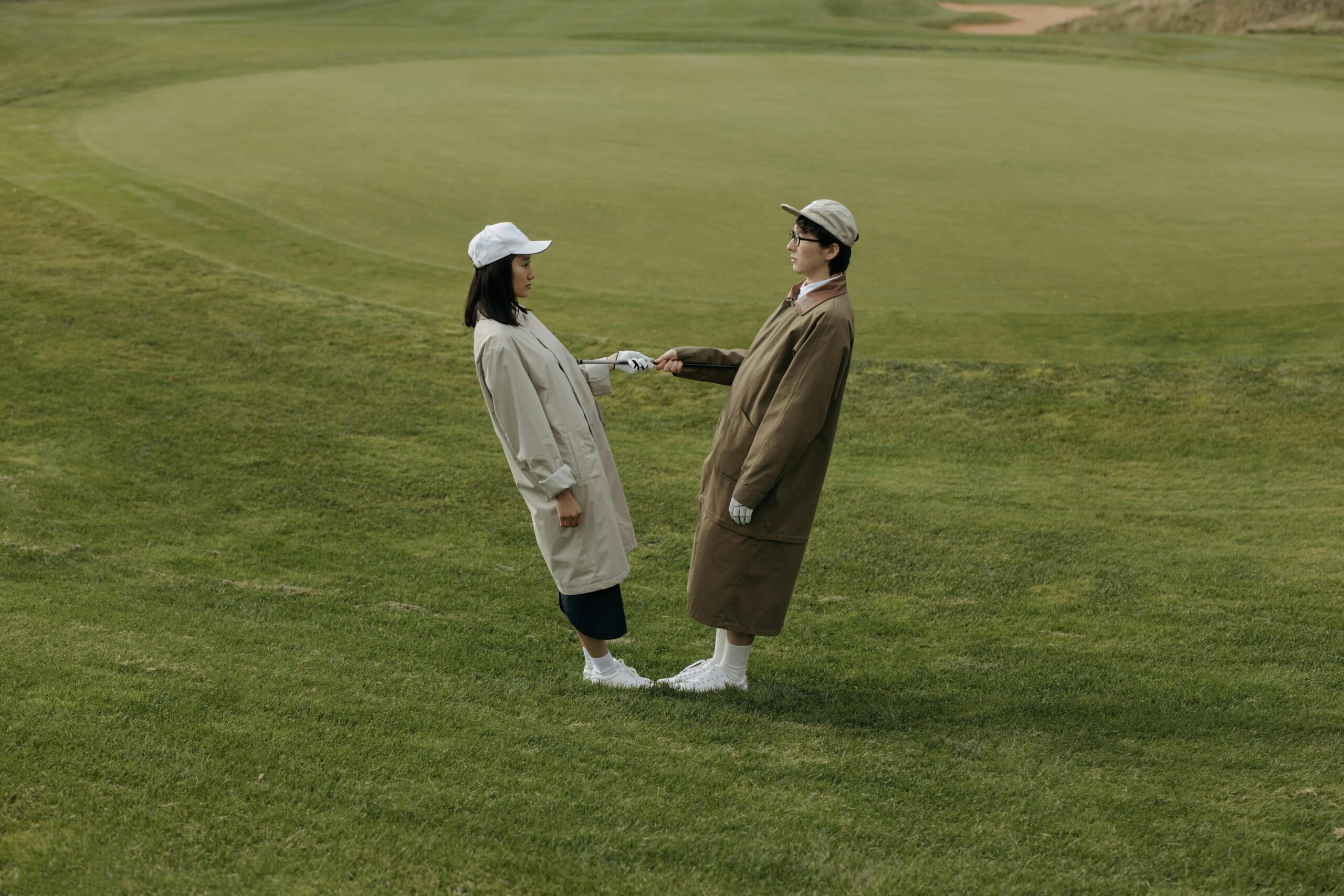 Two stylish golfers posing confidently on the golf course, showcasing premium golf apparel under a clear sky.